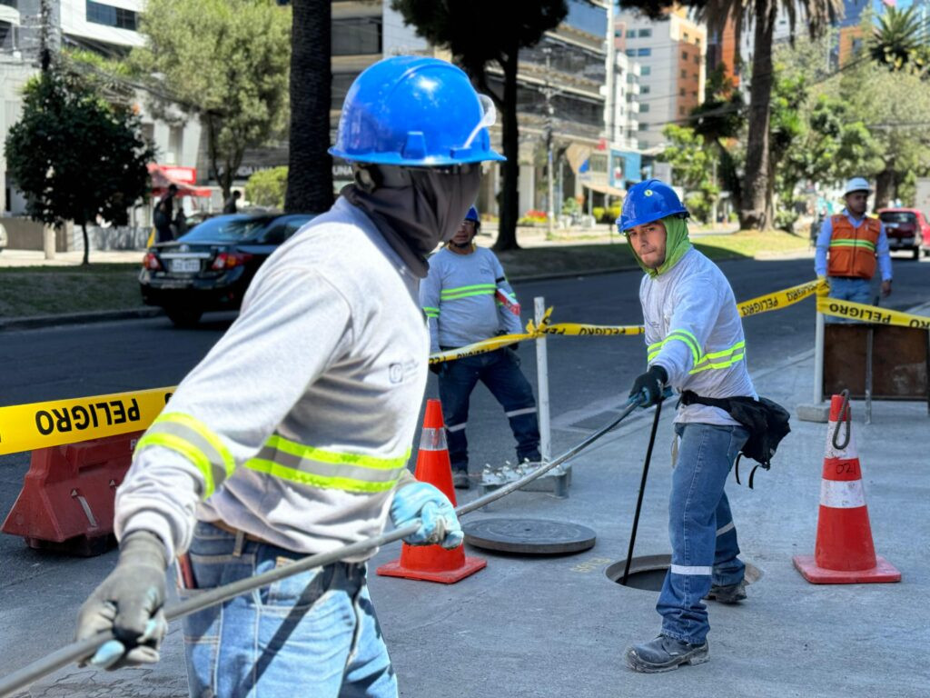 Obras de soterramiento de cables en avenida de Quito con maquinaria y trabajadores instalando canalización subterránea