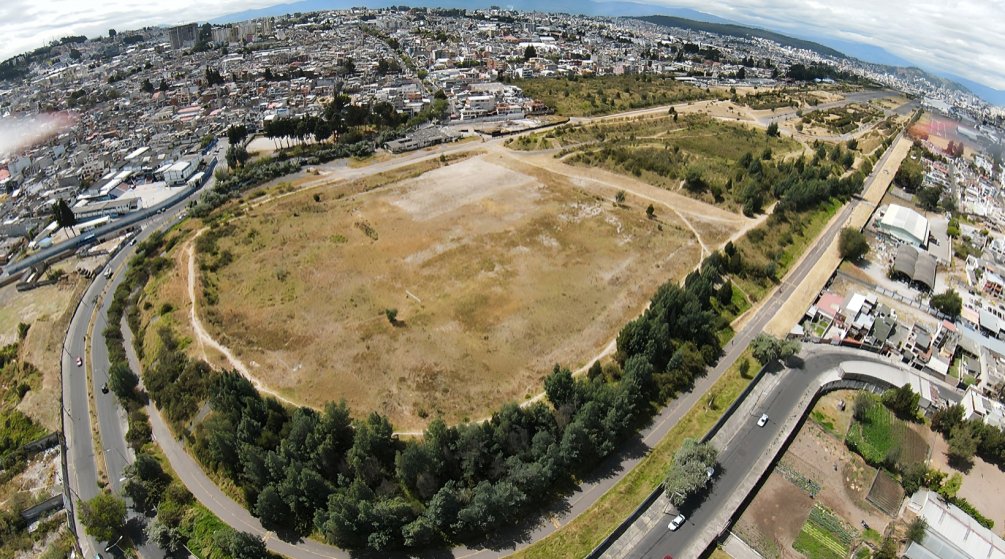 Vista del Parque Bicentenario de Quito con áreas verdes y vehículos abandonados