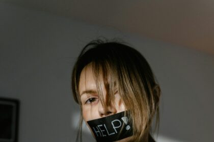 Mujer víctima de violencia digital revisando mensajes amenazantes en su celular.