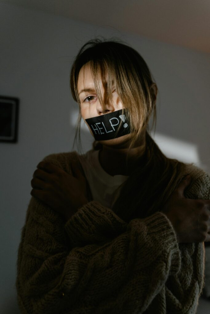Mujer víctima de violencia digital revisando mensajes amenazantes en su celular.