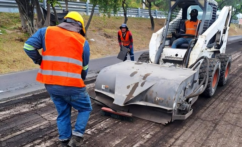 Maquinaria de construcción trabajando en repavimentación en Quito sobre avenida principal con asfalto fresco