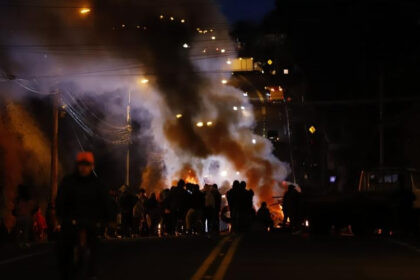 Manifestantes indígenas bloquean carretera durante paro nacional Ecuador 2025 con pancartas y banderas