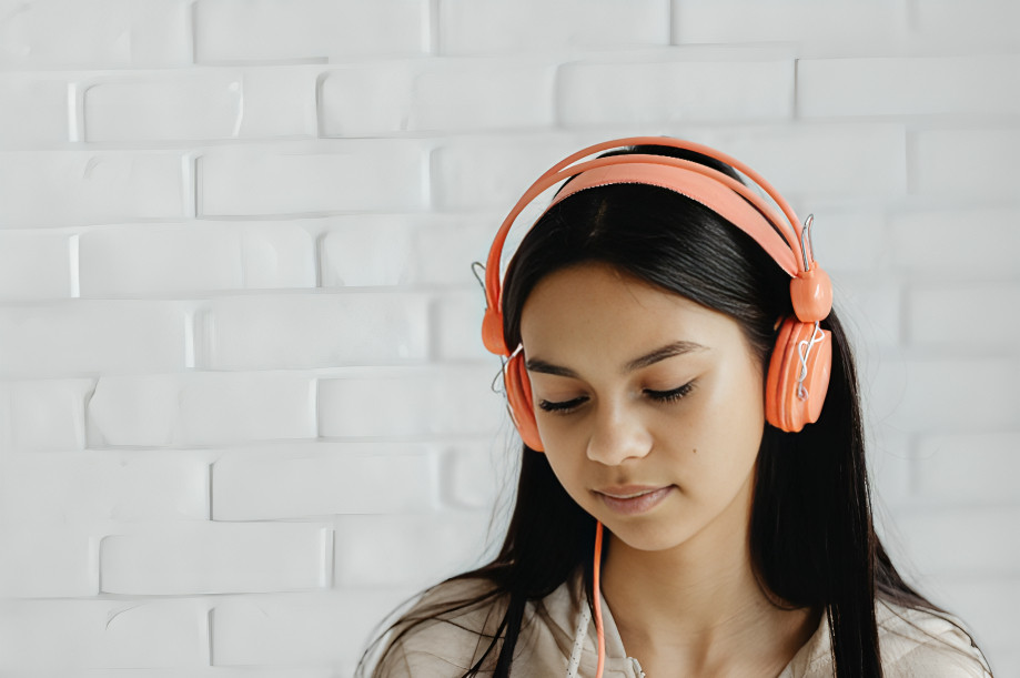 Joven usando auriculares mientras la música que escuchas influye bienestar y salud auditiva según estudios médicos