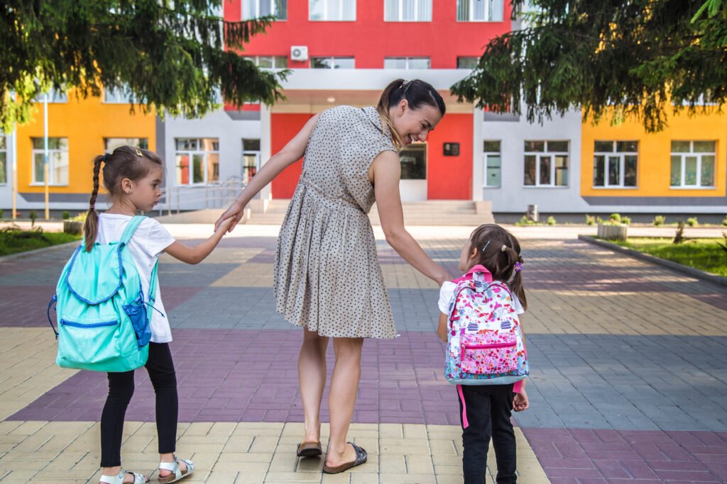 Niño iniciando su primer día de clases acompañado por sus padres en la puerta de la escuela.