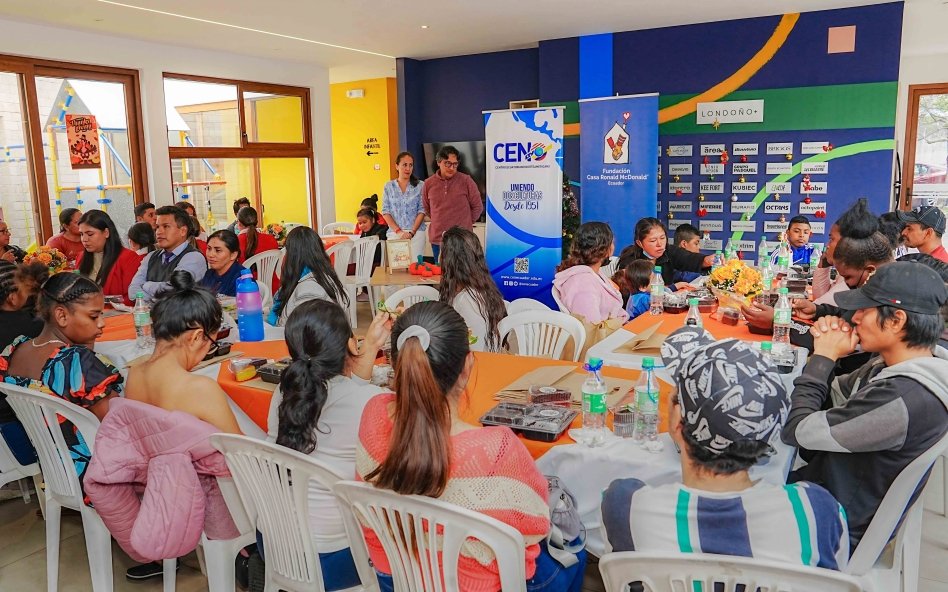 Niños y familias acogidas compartiendo almuerzo de Thanksgiving con representantes del CEN en Guayaquil durante celebración solidaria 2025