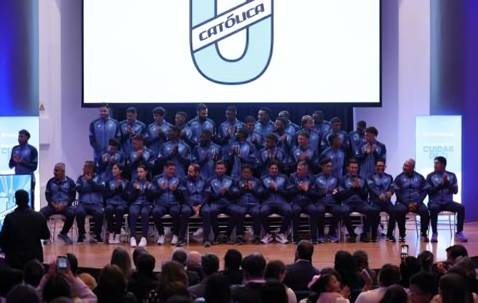 Plantel completo de Universidad Católica posando con las nuevas camisetas 2026 en el auditorio de la PUCE.