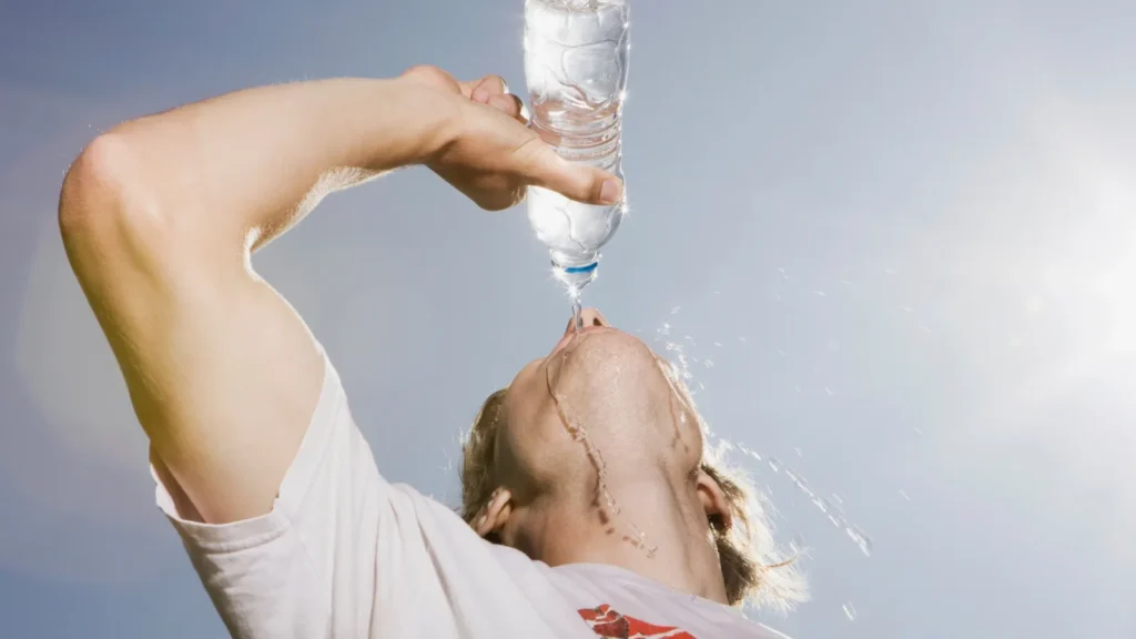 Persona bebiendo agua y alimentos ricos en líquidos para una correcta hidratación diaria