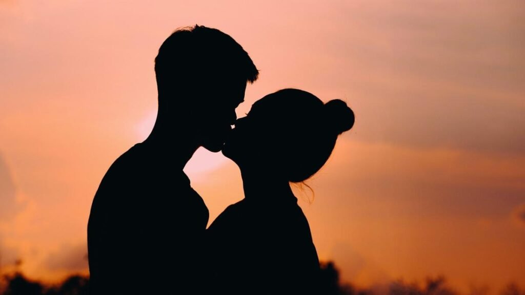 Pareja besándose con una sonrisa radiante, resaltando la importancia de la salud bucal en momentos de intimidad.