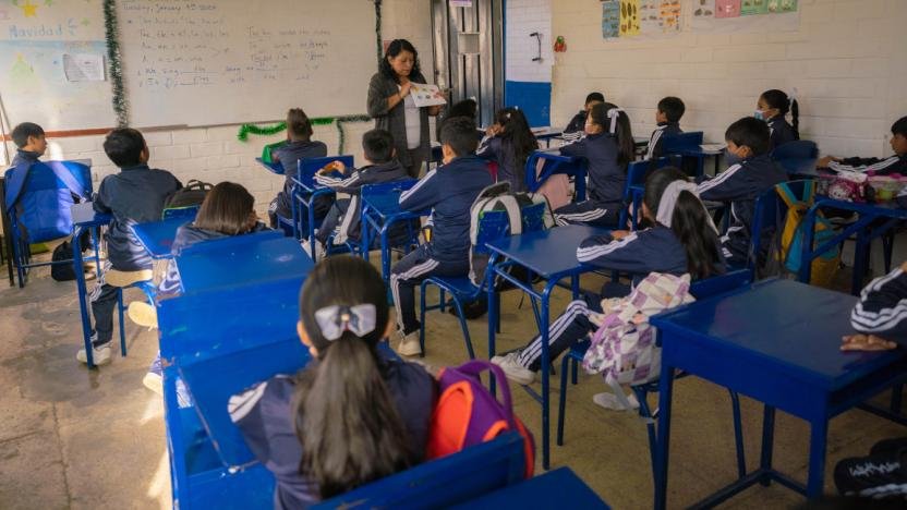 lumnos sonriendo y participando en clase, reflejando un ambiente de salud emocional positiva.