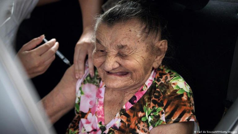 Señora supercentenaria de Brasil sonriendo y celebrando su longevidad, mientras es vacunada