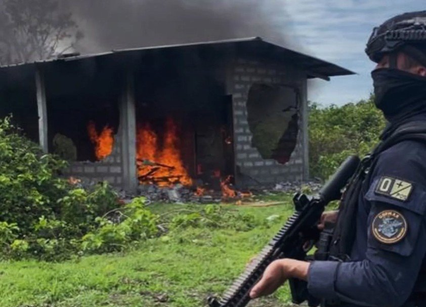 Casa de la mafia Puná custodiada por un policía mientras es destruida durante operativo militar en la isla Puná.