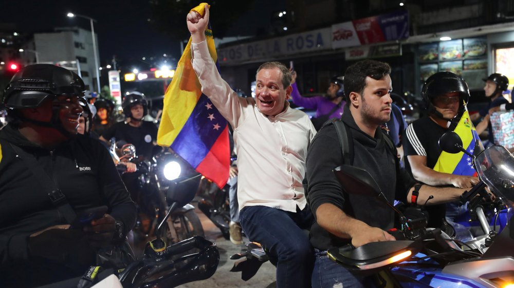 Juan Pablo Guanipa sostiene bandera venezolana en manifestación tras liberación temporal en Caracas el 8 de febrero de 2026