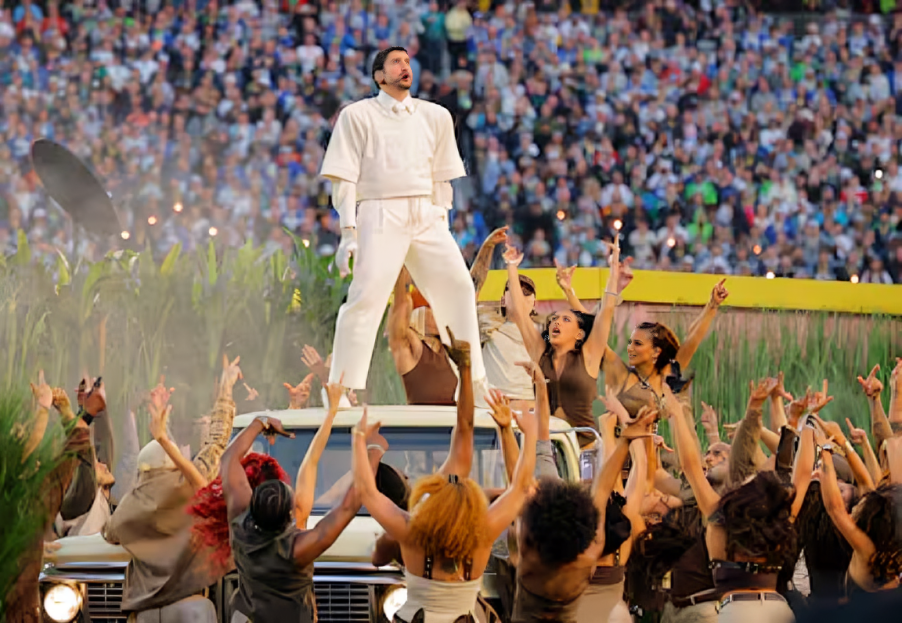 Bad Bunny en el escenario del Super Bowl 2026, con un jersey con el número 64, frente a una recreación de 'La Casita' puertorriqueña.