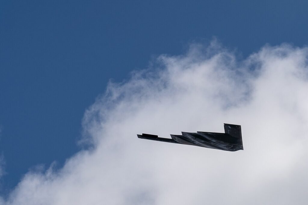 El sigiloso bombardero B-2 Spirit volando sobre terreno montañoso durante una misión nocturna estratégica.