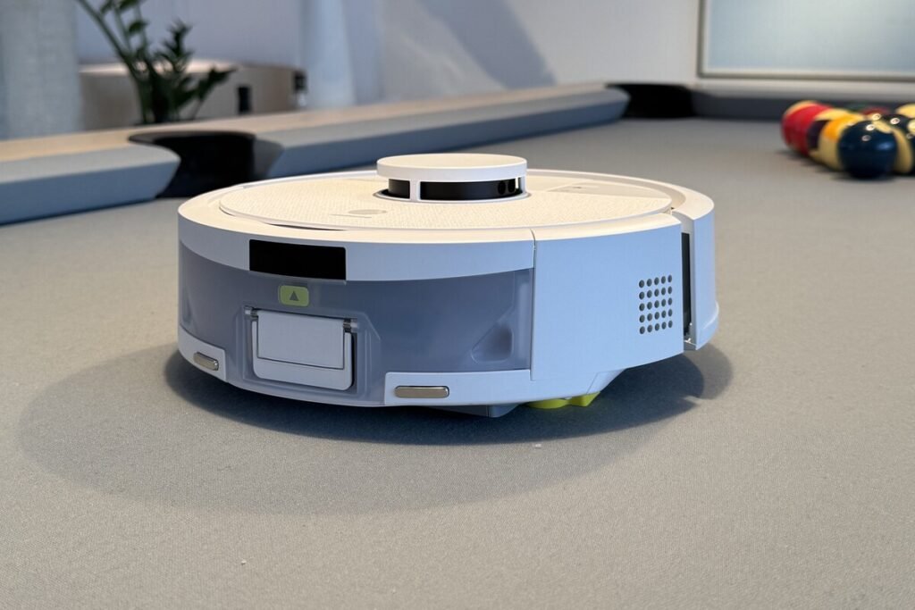 El nuevo iRobot Roomba Mini junto a su base AutoEmpty compacta en un salón minimalista.