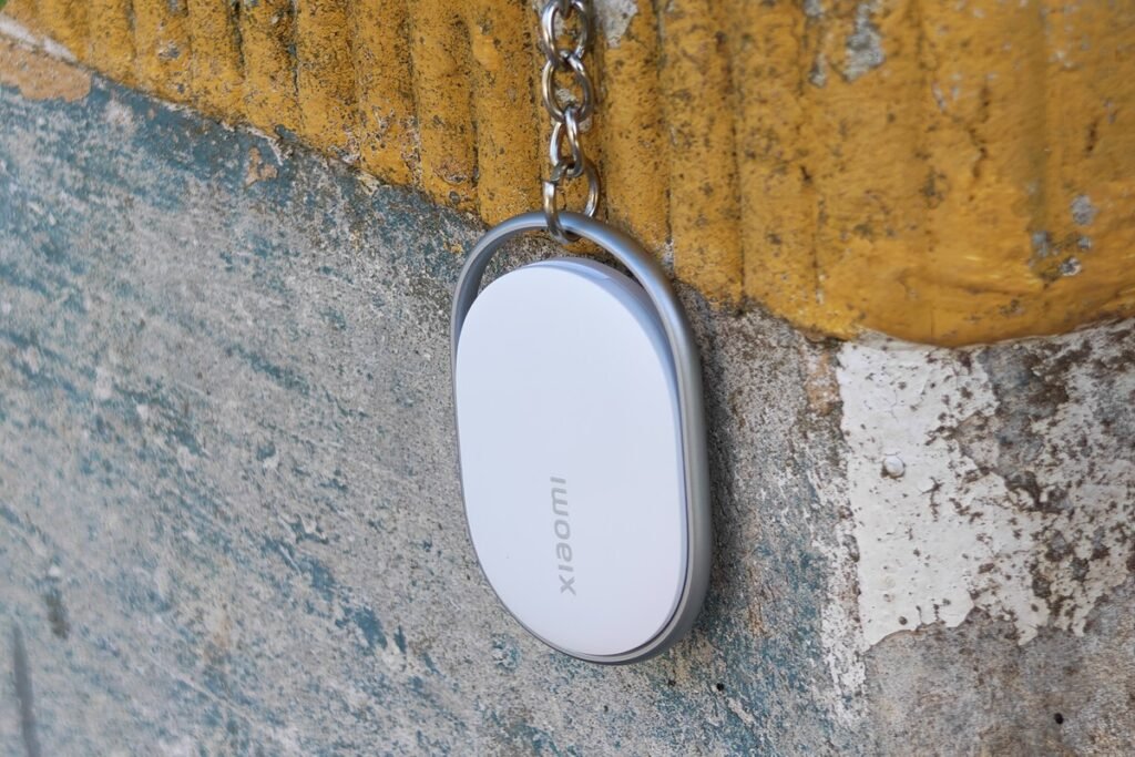 El nuevo localizador Xiaomi Tag color blanco junto a unas llaves, destacando su diseño compacto y funcional.