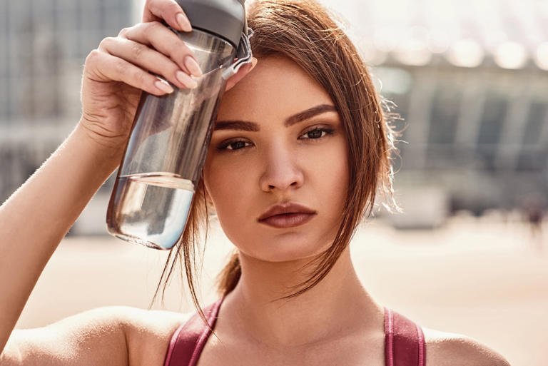 Deportista bebiendo agua en entrenamiento para optimizar su rendimiento y bienestar.
