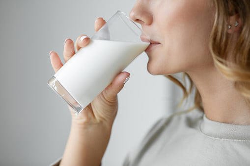 Persona sosteniendo un vaso de leche natural con un fondo saludable y natural.