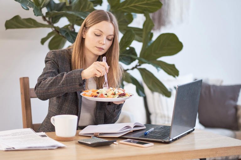 Mujer comiendo una comida saludable con vegetales frescos.