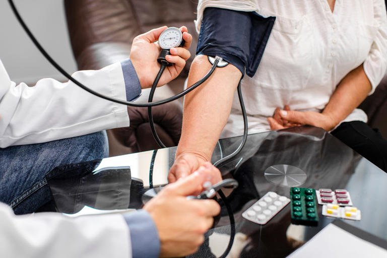 Persona midiendo su presión arterial en casa con monitor digital, promoviendo hábitos saludables para controlar la hipertensión.