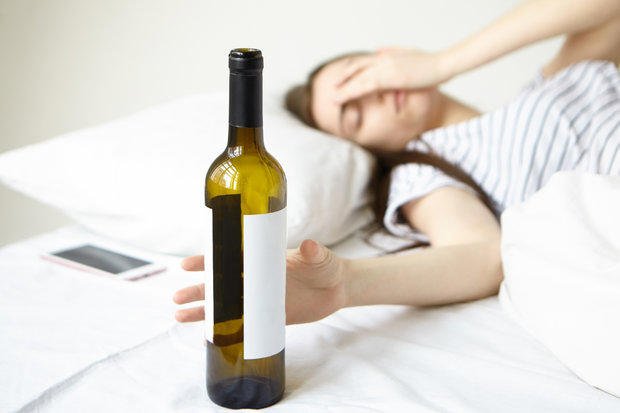 Persona bebiendo un vaso de agua para aliviar la resaca.