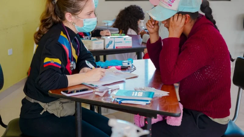 Un grupo de médicos y voluntarios sonriendo mientras atienden a familias en una brigada de salud gratuita en Pelileo.