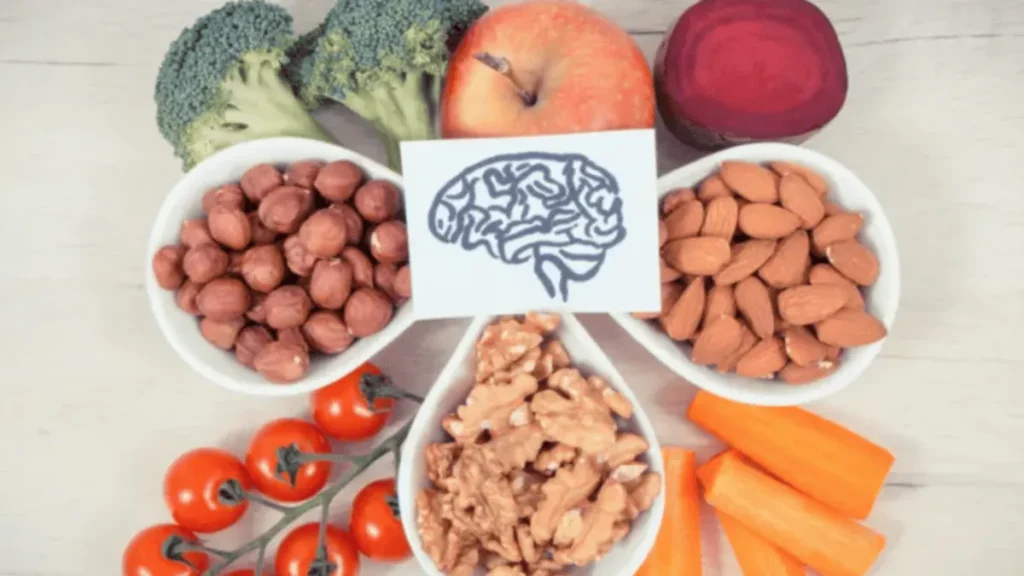 Frutos secos, frutas y verduras frescas sobre una mesa, representando alimentos ricos en fibra para la salud cerebral.