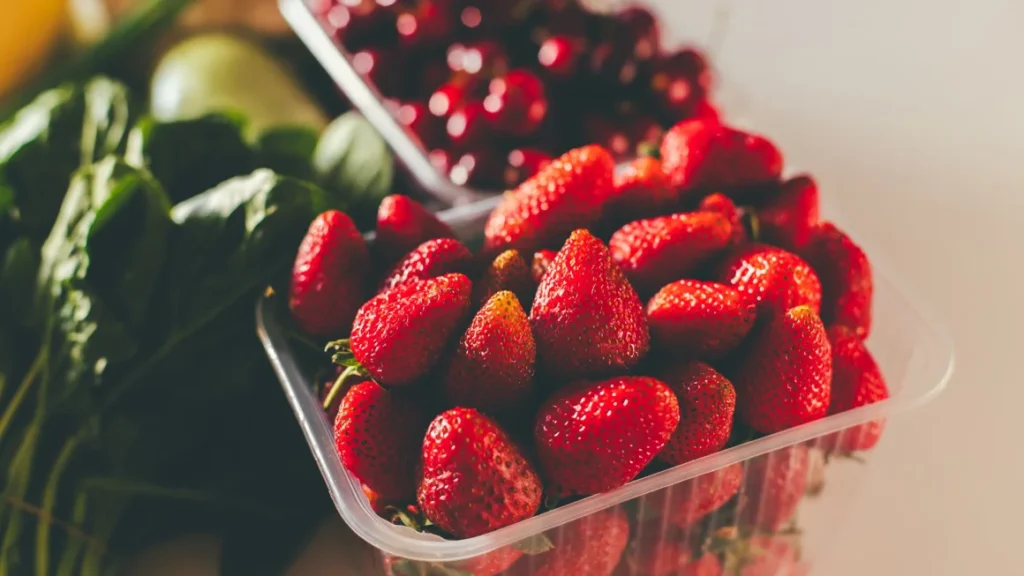Imagen de un racimo de uvas y fresas con gotas de agua, simbolizando frescura pero también la preocupación por los residuos de pesticidas.