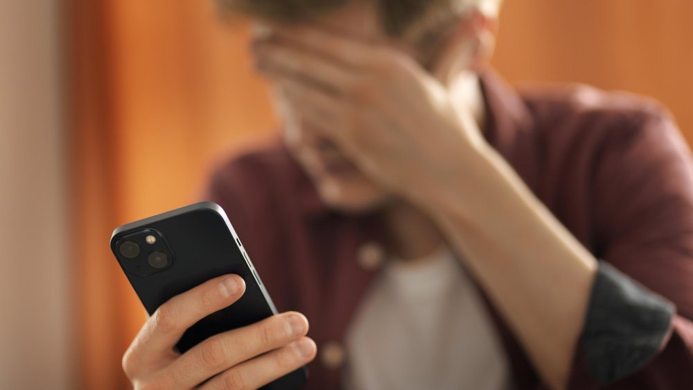 Persona preocupada mirando su celular ante fraudes digitales en Ecuador con inteligencia artificial