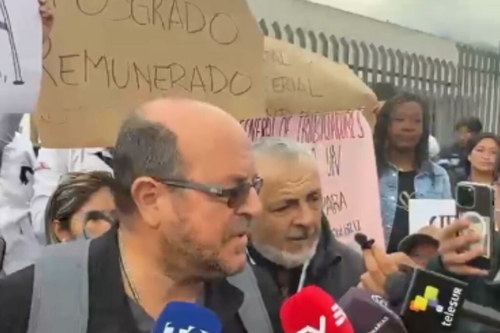 Médicos y enfermeras protestando frente al Hospital Pablo Arturo Suárez en Quito, Ecuador, con pancartas sobre la crisis sanitaria y despidos