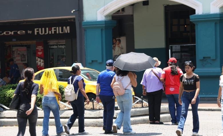 a: Persona aplicando protector solar en la playa de Guayaquil durante un día de calor extremo.