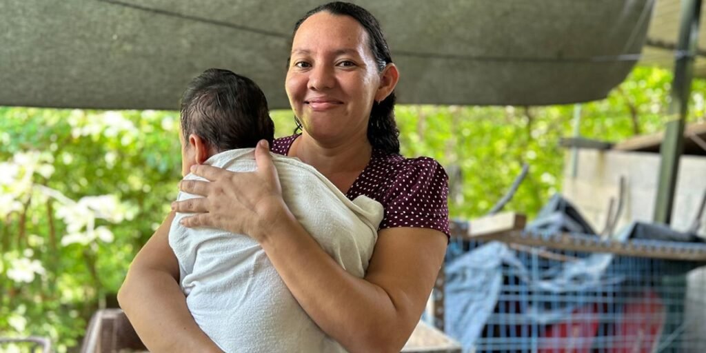 Madre e hija sonriendo en el interior de su nueva casa, un símbolo de vivienda digna y mejor salud.
