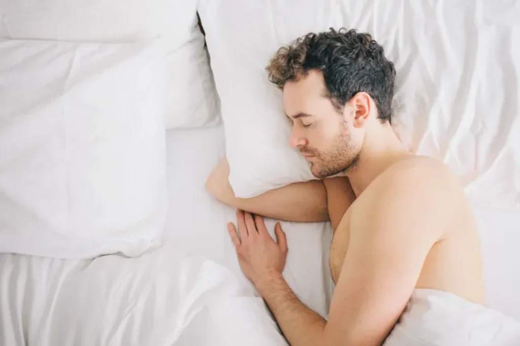 Persona durmiendo plácidamente en una cama fresca, con luz tenue