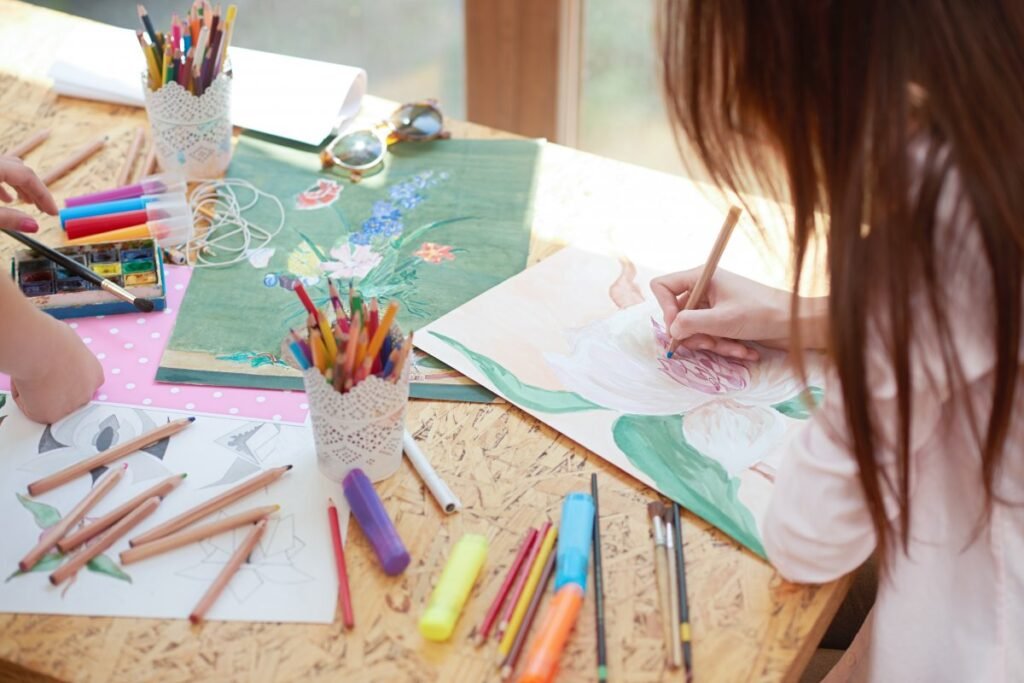 Niños sonriendo mientras participan en un taller de arte, dibujando y expresando sus emociones.