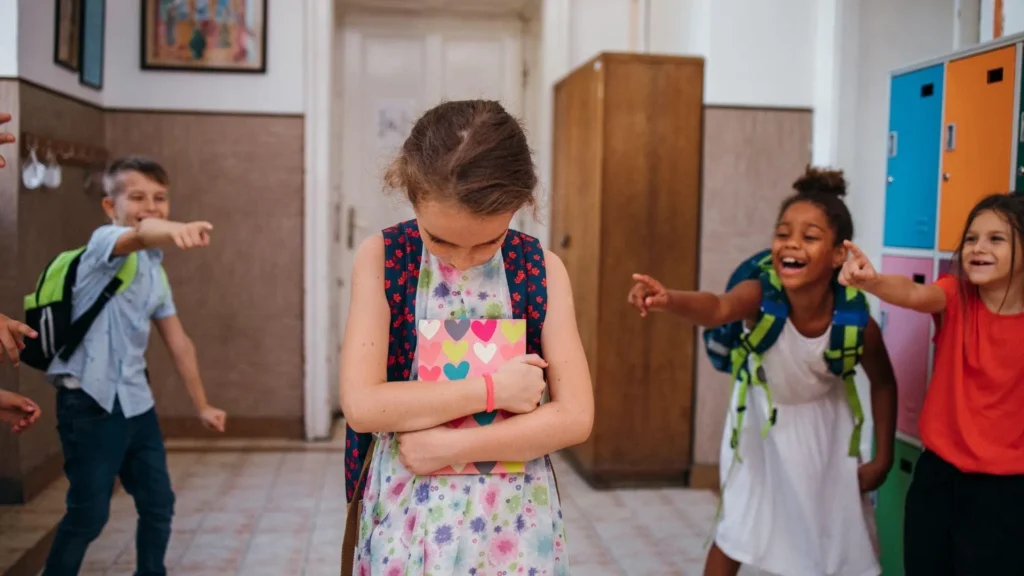 Grupo de niños y adolescentes interactuando en un entorno escolar, con algunos mostrando signos de estrés o aislamiento mientras otros parecen intimidar. La imagen busca ilustrar el impacto multifacético del acoso escolar en la salud mental y la convivencia educativa.