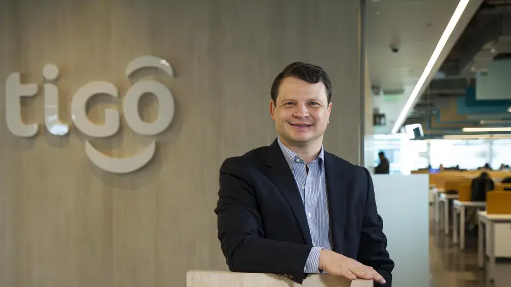 Roberto Andino, CEO de Tigo Ecuador, en oficinas corporativas con logo de Tigo al fondo