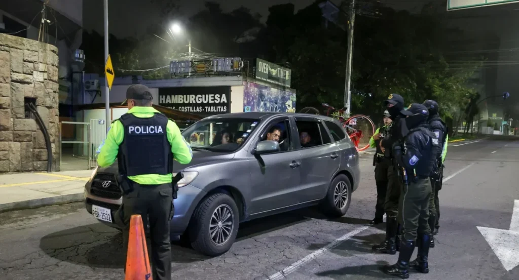 Vista nocturna de las calles de Quito vacías durante la aplicación del toque de queda, con presencia policial al fondo