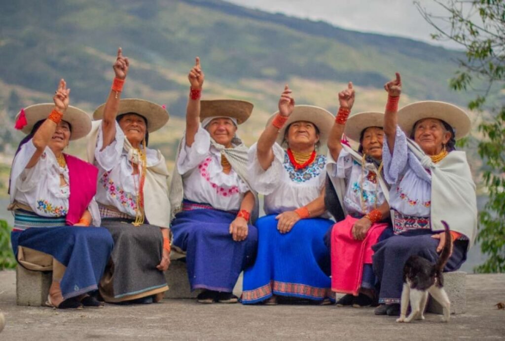 Mujeres parteras ancestrales de Ecuador sosteniendo plantas medicinales y compartiendo saberes tradicionales con otras mujeres en comunidad