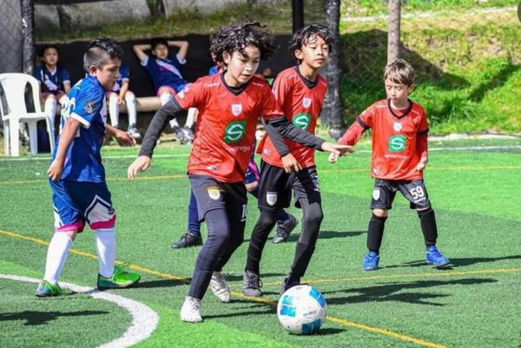 Grupo de infantes ecuatorianos ejecutando ejercicios de control de balón durante un entrenamiento enfocado en los beneficios del fútbol para niños en Ecuador.