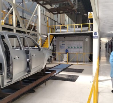 Operarios técnicos ensamblando el chasis de un vehículo moderno dentro de una planta automotriz robotizada en Ecuador.