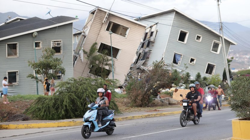 Rescatistas de Protección Civil buscando sobrevivientes entre los bloques de concreto de un edificio colapsado en Caracas.