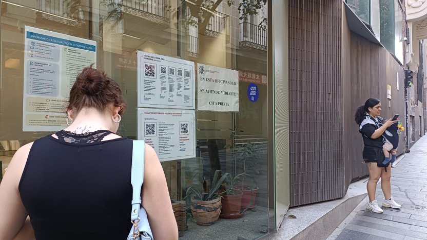 Solicitantes extranjeros revisando documentos legales y contratos cerca de una oficina de tramitación ciudadana en Madrid.