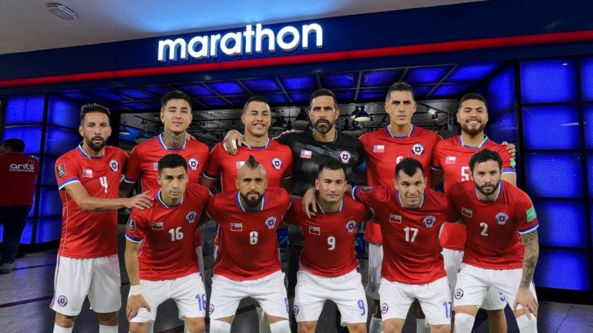 Una camiseta oficial de fútbol de color rojo extendida sobre el césped de un estadio profesional de fútbol.