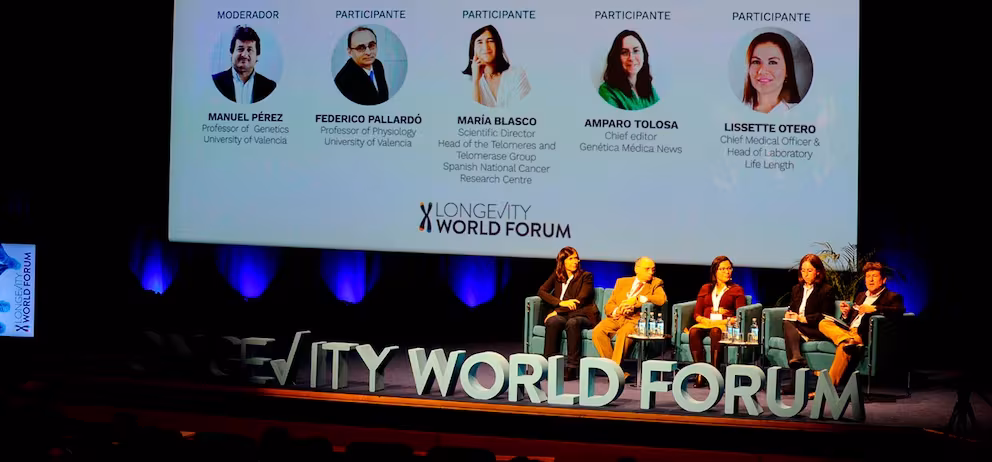 Ponente en escenario con gráficos y logotipo 3D del Longevity World Forum en el suelo hablando sobre medicina preventiva
