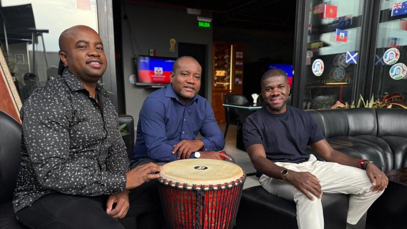 Grupo de personas de la comunidad haitiana en Quito celebrando con tambores y banderas el regreso de Haití al Mundial tras 52 años