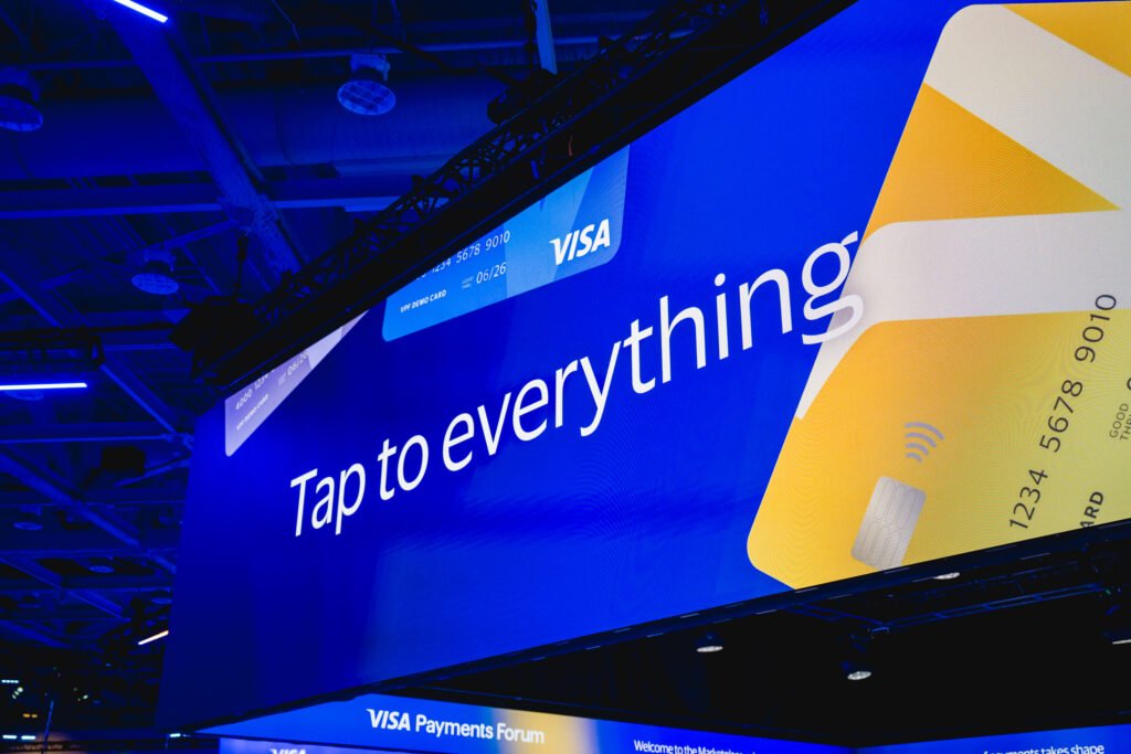 Logotipos de Visa y OpenAI sobre interfaz digital representando alianza de pagos con IA