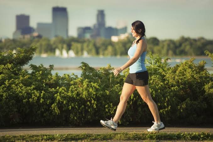 Persona caminando al aire libre en un entorno natural, representando los beneficios de caminar para la salud física y mental