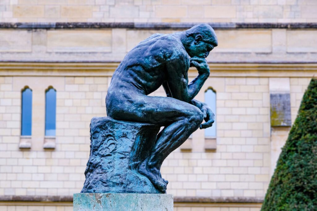 Un primer plano de un busto clásico de Sócrates al lado de una pantalla que despliega líneas de código de una red neuronal, representando cómo las tecnológicas ya compiten por fichar filósofos.