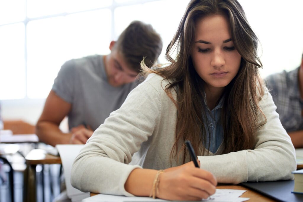 Vista en primer plano de un aula universitaria vacía con un examen escrito a mano sobre un pupitre, ilustrando el fin de las trampas con IA.