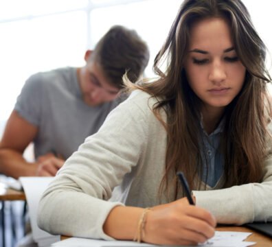 Vista en primer plano de un aula universitaria vacía con un examen escrito a mano sobre un pupitre, ilustrando el fin de las trampas con IA.